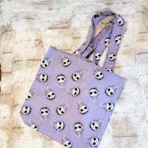 May include: A purple tote bag featuring a repeated pattern of Jack Skellington's face from The Nightmare Before Christmas.