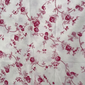 May include: White fabric with a repeating pattern of pink roses and vines.