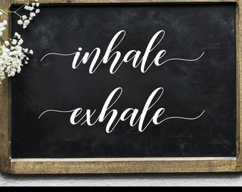 Könnte beinhalten: Eine schwarze Tafel mit den Worten "inhale exhale" in eleganter weißer Schrift. Die Tafel hat einen Holzrahmen und ist mit weißen Blumen verziert. Der untere Teil des Bildes enthält den Text "SVG - PNG - DXF - EPS".