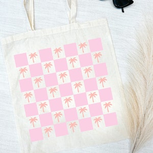 Pode incluir: Uma bolsa tote branca com um padr&atilde;o xadrez rosa e branco com palmeiras rosa.
