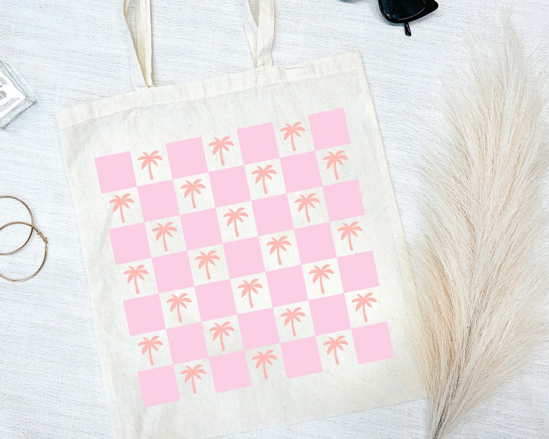 Pode incluir: Uma bolsa tote branca com um padr&atilde;o xadrez rosa e branco com palmeiras rosa.