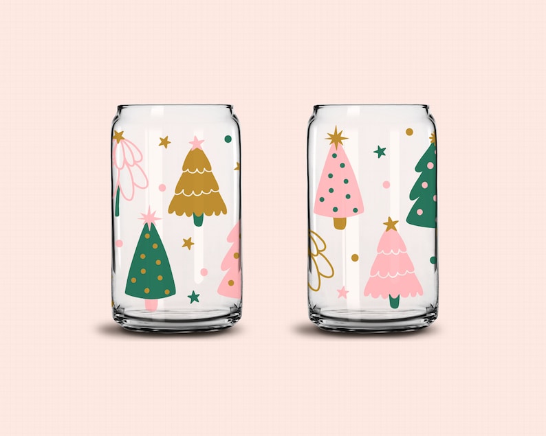 May include: Two clear glass tumblers with a Christmas tree pattern. One tumbler has pink, green, and gold trees. The other tumbler has gold, green, and white trees.