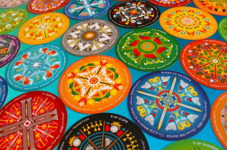May include: A set of colorful round tarot cards with intricate mandala designs. Each card features a different symbol and text, including "The Fool", "Queen of Swords", "Justice", and "8 of Cups".