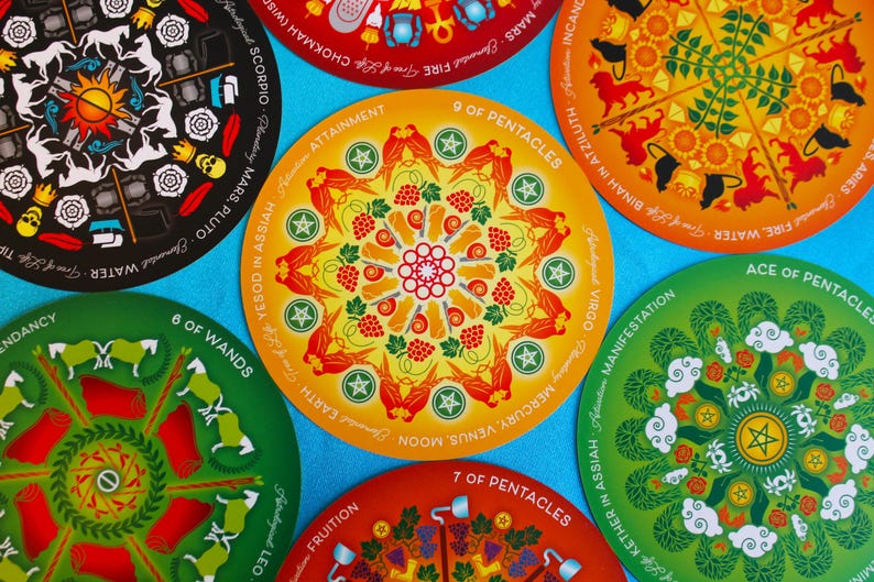 May include: Nine tarot cards with colorful mandala designs. Each card features a different astrological sign and a number. The cards are arranged in a circle on a blue background.