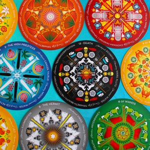 May include: A set of 13 colorful tarot cards with mandala designs. Each card features a different astrological sign and planet, along with the card's name and number. The cards are arranged in a circle on a blue background.