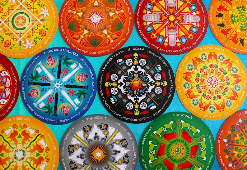 May include: A set of 13 colorful tarot cards with mandala designs. Each card features a different astrological sign and planet, along with the card's name and number. The cards are arranged in a circle on a blue background.