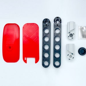 May include: A set of red and black 3D printed parts for a DIY project. The set includes two long black pieces with holes, two short silver pieces, a red piece with a hole, a red piece with a cutout, and a small black rubber piece.