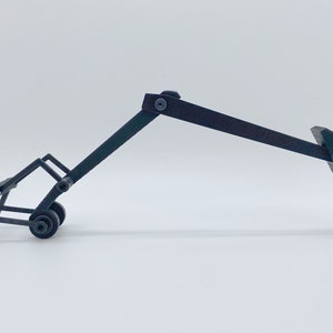 May include: A black metal folding stand with wheels and a hinged arm. The stand is designed to hold a variety of objects, such as a guitar or a microphone.