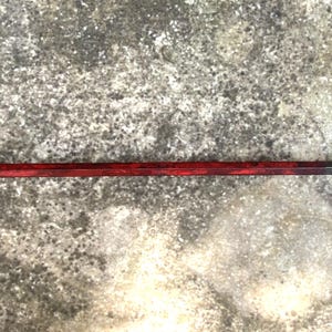 May include: A metal pry bar with a curved end and a pointed tip. The handle is painted a deep red, transitioning to a darker color near the ends. The tool is designed for leverage and prying.