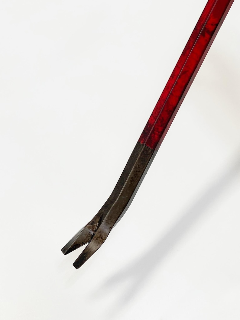 May include: A red and black pry bar, a hand tool used for prying objects apart. The tool has a flat, angled head and a long, straight handle. The handle is painted red, and the head is black.