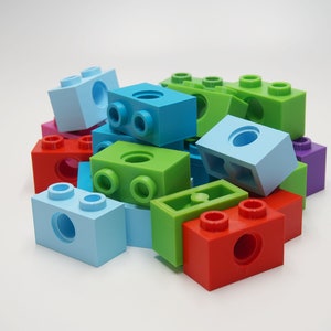 May include: A pile of colorful plastic building blocks in various shapes and sizes. The blocks are blue, green, red, purple, and light blue.