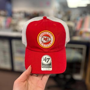 May include: Red and white baseball cap featuring the Kansas City Chiefs logo. The cap has a red front panel and brim, with a white mesh back. The team logo is embroidered on the front. The cap is adjustable.