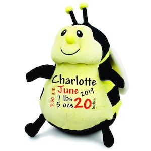 May include: A yellow and black bee plush toy with embroidered details. The bee has a smiling face, black eyes, and a yellow nose. The bee is personalized with the name "Charlotte", the date "June 2019", the time "3:30 a.m.", the weight "7 lbs 5 ozs", and the length "20 inches".