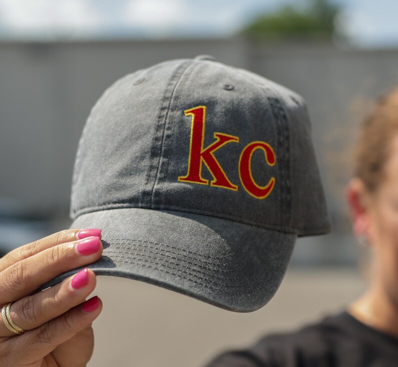 Puede incluir: Una gorra de b&eacute;isbol de algod&oacute;n gris lavado con un "KC" bordado en rojo y amarillo en la parte delantera.