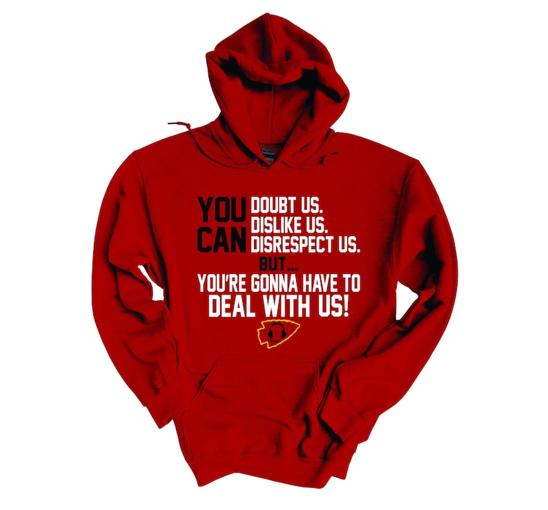 Puede incluir: Sudadera con capucha roja con un estampado gr&aacute;fico en blanco y negro que dice "You doubt us. Dislike us. Can disrespect us. But... You're gonna have to deal with us!" y un logotipo amarillo y rojo.