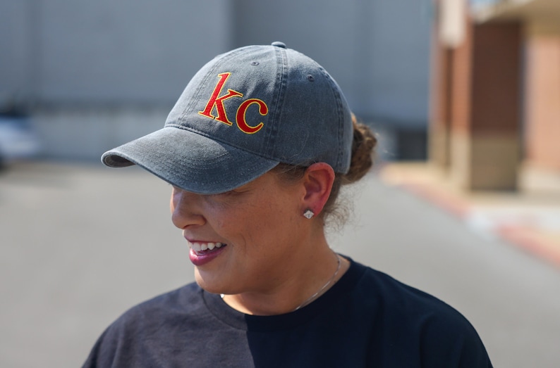 Puede incluir: Una gorra de b&eacute;isbol gris oscuro con un "KC" bordado en rojo y amarillo en la parte delantera.