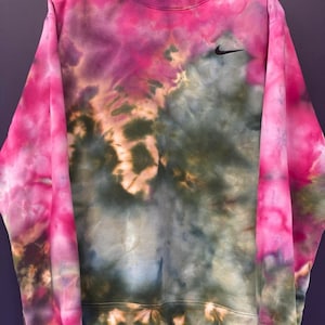 Puede incluir: Una sudadera de color rosa, verde y azul tie-dye con un logotipo de Nike negro en el pecho.