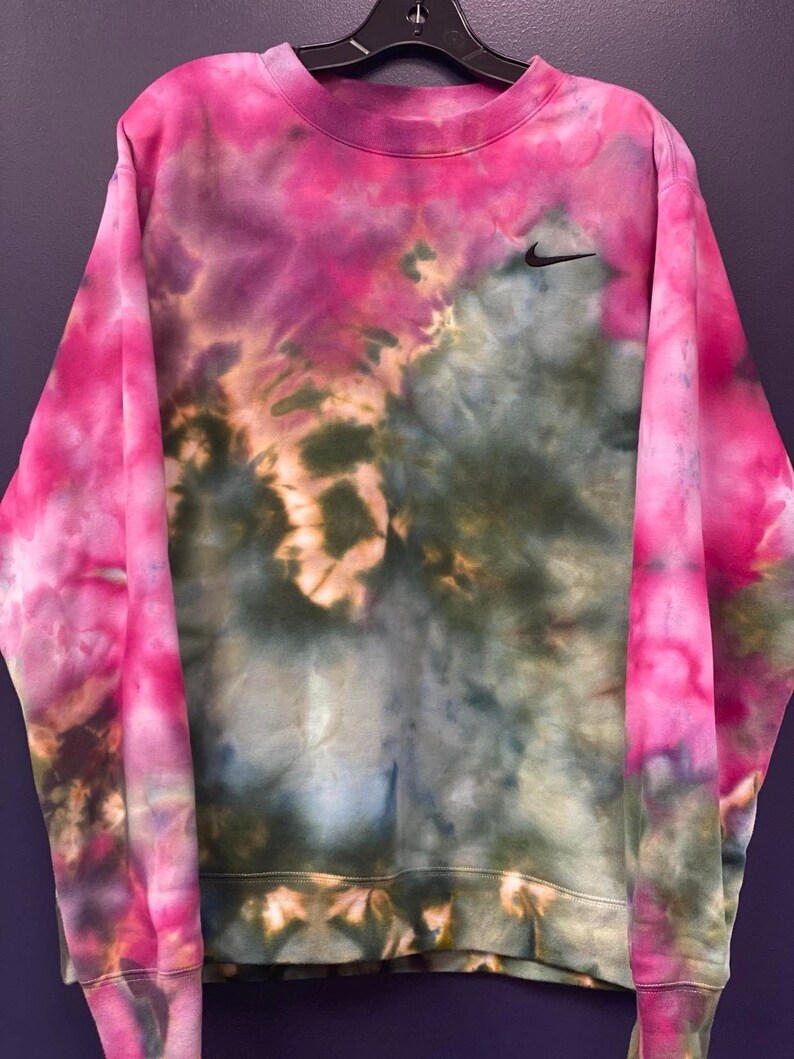 Puede incluir: Una sudadera de color rosa, verde y azul tie-dye con un logotipo de Nike negro en el pecho.
