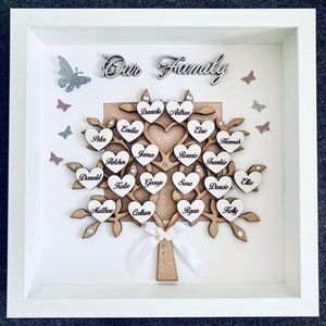 May include: A framed wooden family tree with the words "Our Family" at the top. The tree is decorated with hearts, each with a name written on it. The names include Danniella, Arthur, Emilia, Elsie, Peter, Hannah, James, Ronnie, Frankie, Fletcher, Donald, Katie, George, Sara, Ellie, Daucie, Matthew, Callum, Ryan, and Kelly.