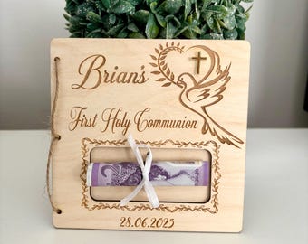 Könnte beinhalten: Hellbraune Holz-Geschenkbox zur Erstkommunion mit dem Namen "Brian's" und dem Datum 28.06.2025 eingraviert. Das Design zeigt eine Taube und ein Kreuz, sowie ein Fenster für Geld.