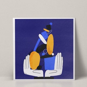 Può includere: Stampa d'arte astratta con un design geometrico blu, giallo e bianco su uno sfondo blu scuro. Due mani bianche tengono il design al centro della stampa.