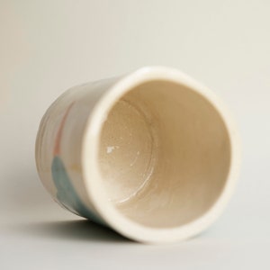 a picture of the lay down cup where you see the inside of the cup and the transparent glaze finishing in the bottom of the piece. It's smooth and beige transparent.