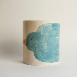 The front part of the cup, with you see the eye of the bird, a small black dot and the turquoise paintbrushes and cracks on the craquelure glaze.