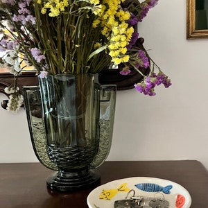 the bowl being used in a wooden table top with a glass vase with flowers on left side. The fish bowl has house keys on it.