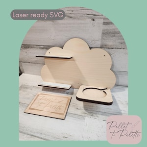 Könnte beinhalten: Ein hölzernes, wolkenförmiges Regal mit zwei kleinen Regalen und einem quadratischen Untersetzer. Der Text "Laser ready SVG" befindet sich in einem hellgrauen Rechteck. Der Text "Pallet to Palette" befindet sich in einem rosa Rechteck.