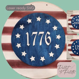Pode incluir: Uma placa redonda de madeira com tema patriótico. Apresenta um círculo azul com estrelas brancas e o número "1776". O fundo tem listras vermelhas e brancas, semelhantes à bandeira americana. Placas menores adicionais estão incluídas.