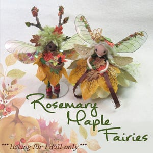 May include: Two handmade fairy dolls with leaf-like skirts and wings. One doll has a crown and the other has twig-like antlers. The text "Rosemary Maple Fairies" is written in green cursive. The listing is for one doll only.