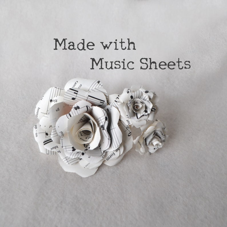Puede incluir: Tres rosas blancas de papel hechas con partituras. Las rosas est&aacute;n dispuestas en un racimo. El texto "Made with Music Sheets" est&aacute; escrito sobre las rosas.