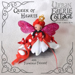 May include: A handmade doll dressed as the Queen of Hearts from Alice in Wonderland. She has red hair, a red and white dress, and a crown. She is holding a pink flamingo.