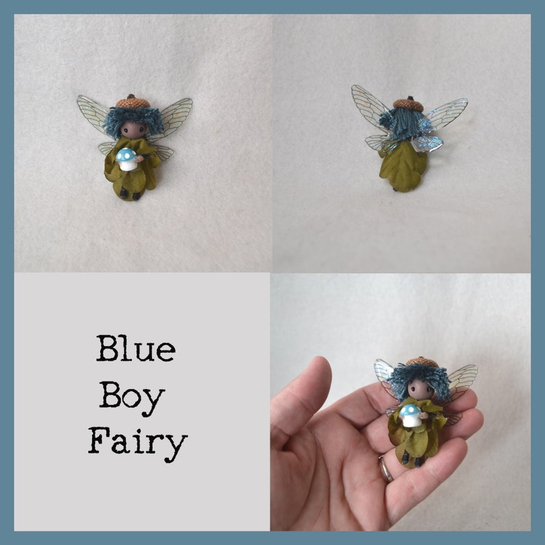 Op de afbeelding: Een kleine blauwe en groene feepop met vleugels, die een blauwe paddenstoel vasthoudt. De fee draagt ​​een bruine eikelhoed en een groene jurk. De tekst "Blue Boy Fairy" is zichtbaar in de afbeelding.