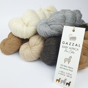 May include: A collection of six balls of yarn in various shades of brown, beige, and grey. The yarn is labelled "GAZZAL BABY ALPACA Pure Colors" and includes the details: 55% Baby Alpaca, 45% Merino Wool, 100 g - 3.52 oz, ca. 320 mt - 349 yd.