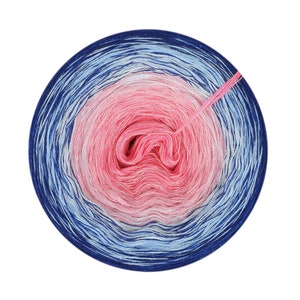 May include: A skein of yarn with a gradient of pink, white, and blue colors. The yarn is wound into a circle and has a sparkly finish.