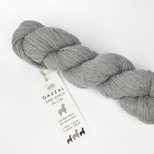 May include: A skein of grey yarn labelled "GAZZAL BABY ALPACA Pure Colors" with the fibre content and yardage listed on the label. 55% Baby Alpaca, 45% Merino Wool, 100 g, 3.52 oz, ca. 320 m, 349 yd.