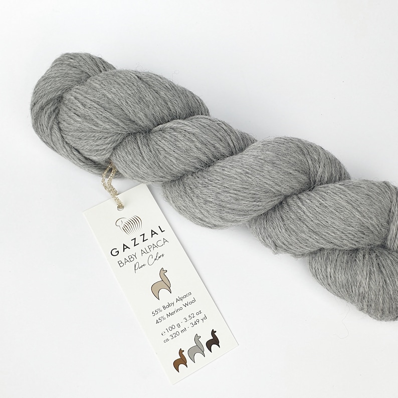 May include: A skein of grey yarn labelled "GAZZAL BABY ALPACA Pure Colors" with the fibre content and yardage listed on the label. 55% Baby Alpaca, 45% Merino Wool, 100 g, 3.52 oz, ca. 320 m, 349 yd.