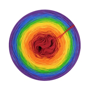 Op de afbeelding: Een bol regenboogkleurig garen met een rode kern. Het garen is in een cirkel gewikkeld en klaar om te gebruiken voor breien of haken.