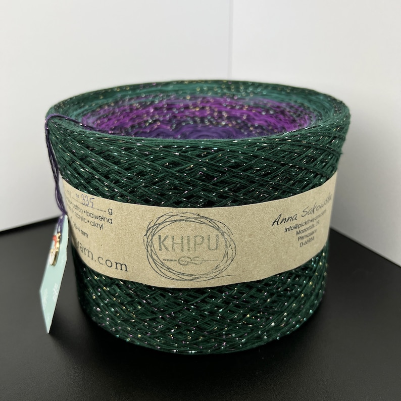 May include: A skein of green yarn with silver glitter, wound on a cardboard spool. The yarn is labeled "Khipu" and "Anna Sakowska".