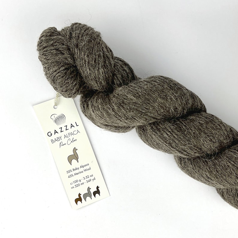 May include: A skein of brown yarn labelled "GAZZAL BABY ALPACA Pure Colors" with a label listing the yarn composition as 55% baby alpaca and 45% merino wool. The label also states that the skein weighs 100 grams (3.52 ounces) and contains 320 metres (349 yards) of yarn.