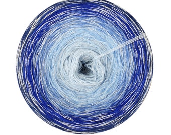 Puede incluir: Una bola de hilo azul y plateado con un degradado de color de azul oscuro a azul claro. El hilo está enrollado en un círculo y el extremo del hilo cuelga del centro.