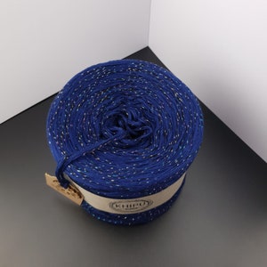 May include: A skein of navy blue yarn with iridescent glitter threads. The yarn is wound into a ball and has a label that says "KHIPU".