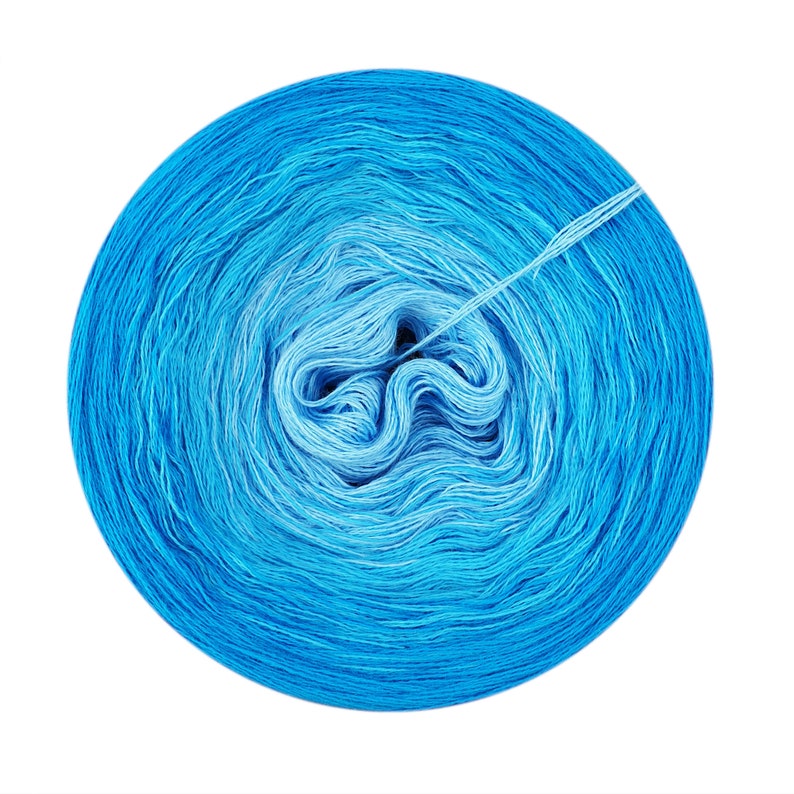 May include: A skein of blue yarn wound into a ball. The yarn is a gradient of light blue to dark blue.