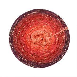 May include: A skein of yarn in a gradient of red, orange, and purple with gold metallic thread woven throughout.