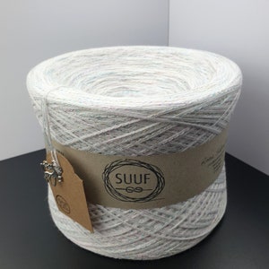 May include: A white yarn skein with iridescent glitter threads. The yarn is wrapped around a brown cardboard tube with a label that says "SUUF" in a black circle.