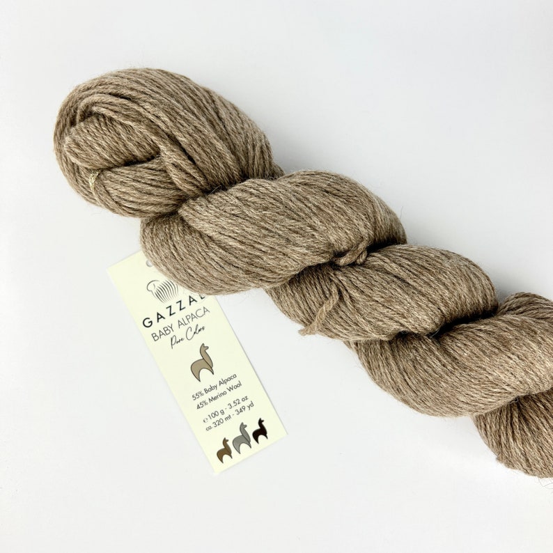 May include: A skein of brown yarn labelled "GAZZAL BABY ALPACA Pin Clos" with the yarn composition and yardage information: 55% Baby Alpaca, 45% Merino Wool, 100g - 3.52 oz, 320 m - 349 yd.
