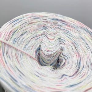 May include: Close-up of a white ball of yarn with colourful streaks of blue, pink and yellow.