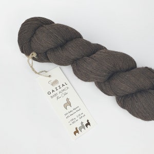 May include: A skein of brown GAZZAL Baby Alpaca yarn with a label that reads "GAZZAL Baby Alpaca Pure Colors 55% Baby Alpaca 45% Merino Wool 100 g - 3.52 oz ca. 320 mt - 349 yd".