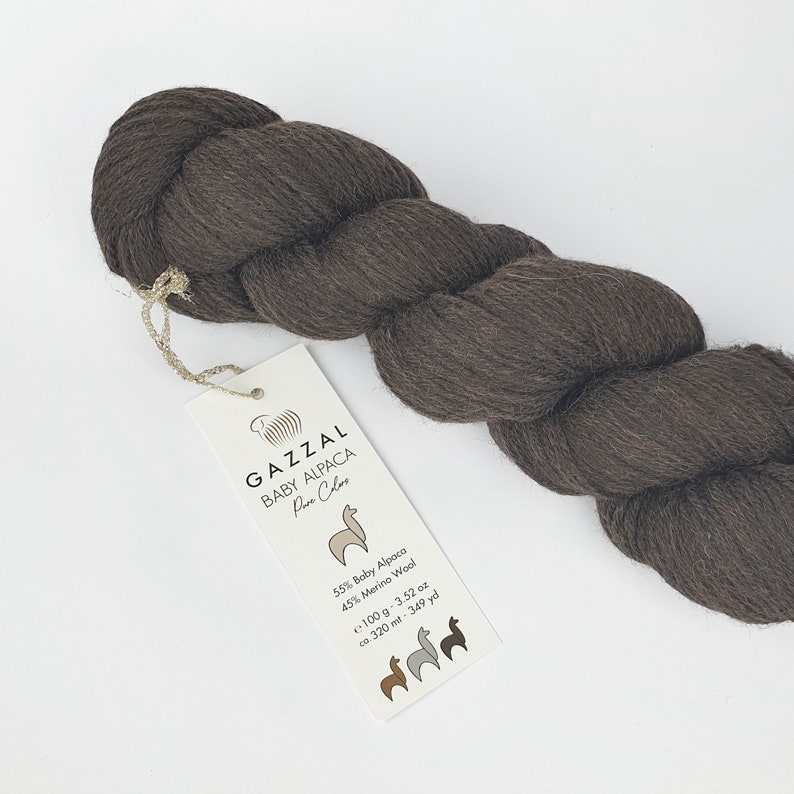 May include: A skein of brown GAZZAL Baby Alpaca yarn with a label that reads "GAZZAL Baby Alpaca Pure Colors 55% Baby Alpaca 45% Merino Wool 100 g - 3.52 oz ca. 320 mt - 349 yd".
